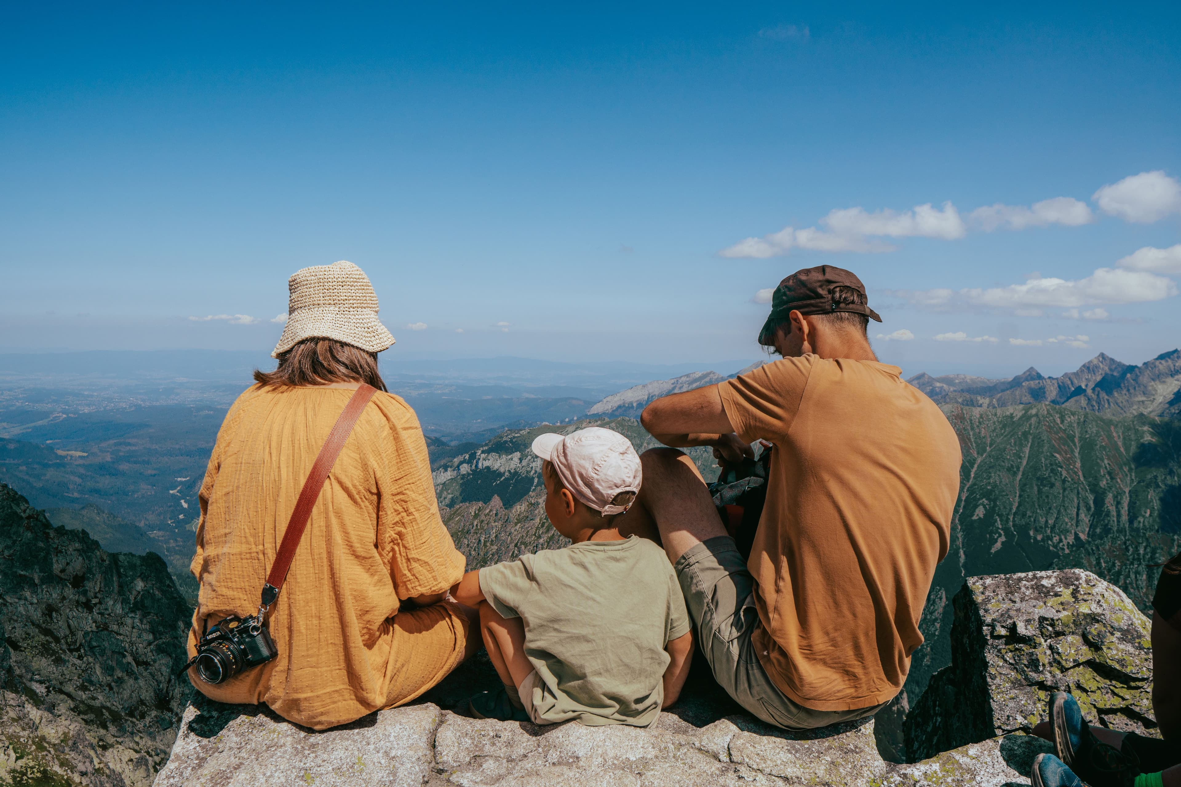 A family sitting together on a mountaintop, looking out over the view.